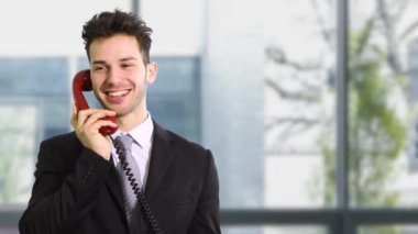 Eski bir kırmızı telefonla konuşan bir iş adamı.