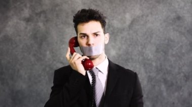 İş adamı telefonda konuşamıyor çünkü ağzı koli bandıyla bağlanmış.