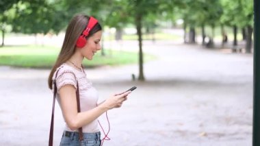 Akıllı telefonunu kullanırken parkta yürüyen kadın