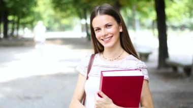 Gülümseyen öğrenci açık tutarak kitap