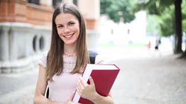 Gülümseyen öğrenci açık tutarak kitap