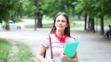 Gülümseyen öğrenci dışarıda yürüyor.