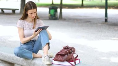 Bir bankta oturan tablet ile kız