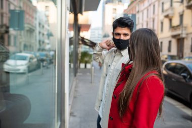 Covid ve Coronavirus alışveriş yapıyor, genç bir çift şehirde yürüyor.