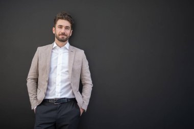 Siyah bir duvarın önünde gülümseyen adam.