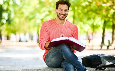 Yakışıklı genç adam parkta bankta kitap okuma