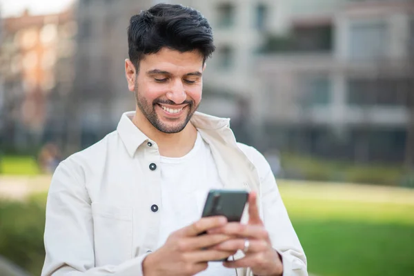 Glimlachende Man Met Behulp Van Zijn Smartphone Tijdens Het Wandelen — Stockfoto