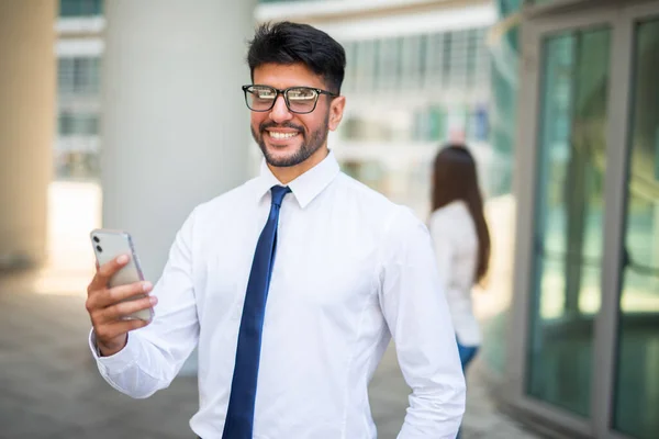 Smiling businessman using his cellphone in front of colleague, teamwork concept