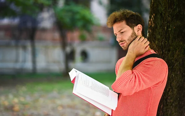 Genç Bir Erkek Öğrenci Parkta Bir Ağaca Yaslanmış Kitap Okuyor — Stok fotoğraf