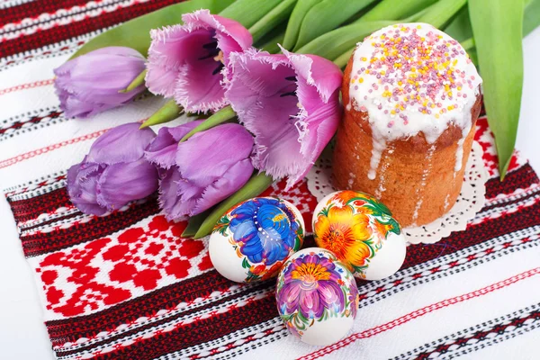 Пасхальные яйца, торт и тюльпаны на полотенце — стоковое фото