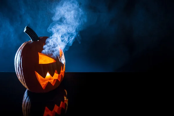 Räucherkürbis mit Kerze zu Halloween auf schwarzem Hintergrund — Stockfoto