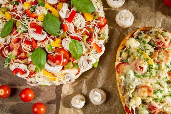 Closeup of baked pizza and raw with vegetables — Stock Photo, Image