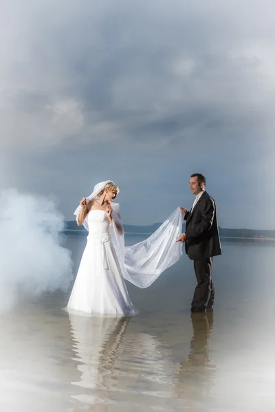 Young couple standing in a lake in the fog — Stock Photo, Image