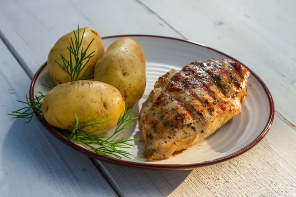 Roasted chicken breast served with potatoes and dill on old plan — Stock Photo, Image