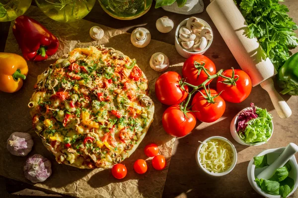 Pizza casera y verduras frescas en mesa vieja — Foto de Stock