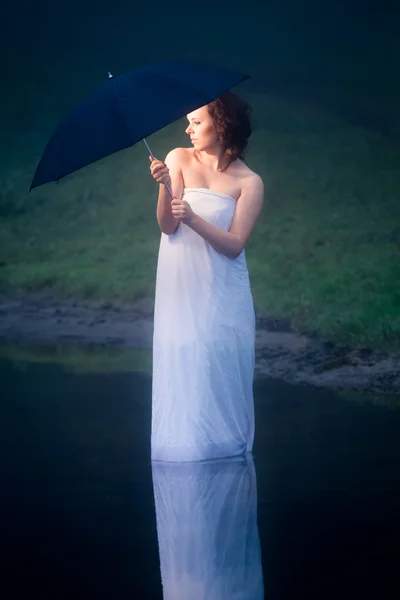 Protective umbrella protects woman in cold lake — Stock Photo, Image