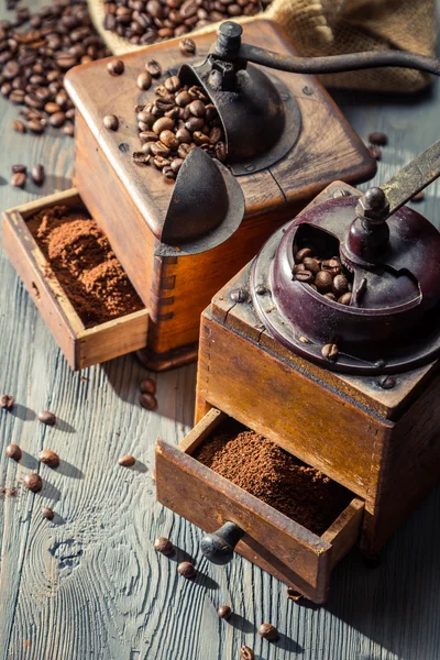 Old coffee grinders with burlap sack on wooden table — Stock Photo, Image