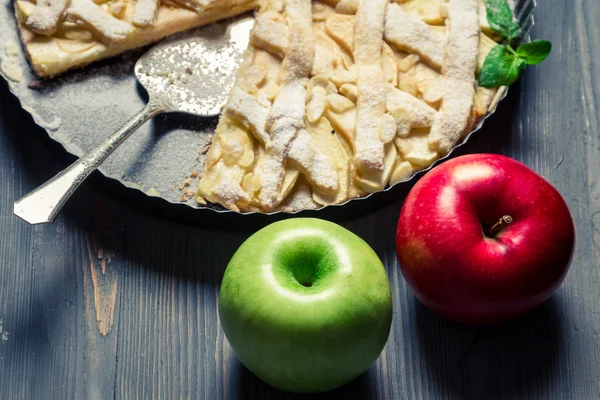 Zwei Äpfel und frisch gebackener Apfelkuchen auf altem blauen Tisch — Stockfoto