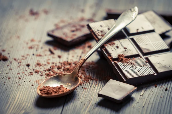 Cacao en polvo sobre cuchara y fondo de chocolate negro — Foto de Stock