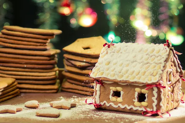 Decorating gingerbread cottage on Christmas tree background — Stock Photo, Image