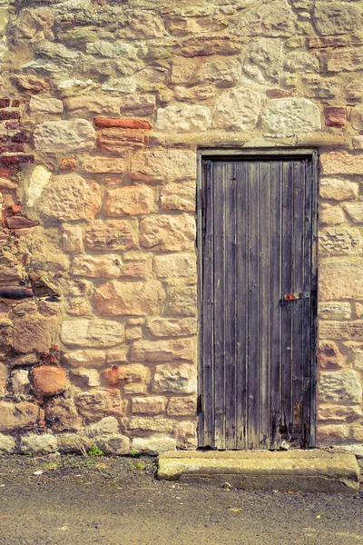 Porta de madeira vintage velho na parede de pedra — Fotografia de Stock