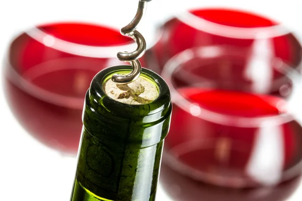 Opening wine bottle on red glass background — Stock Photo, Image