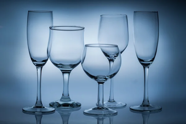 Különböző típusú üres poharak, kék háttérrel — Stock Fotó