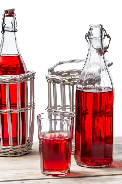 Vintage bottles in basket with juice on white background — Stock Photo, Image