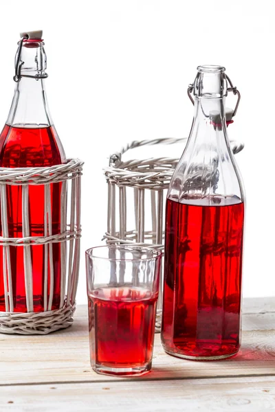 Garrafas em cesta com suco vermelho no fundo branco — Fotografia de Stock