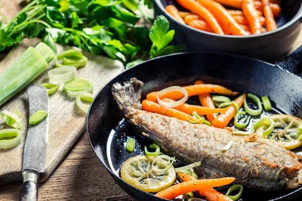 Крупный план свежеобжаренной рыбы с луком-порей и морковью — стоковое фото