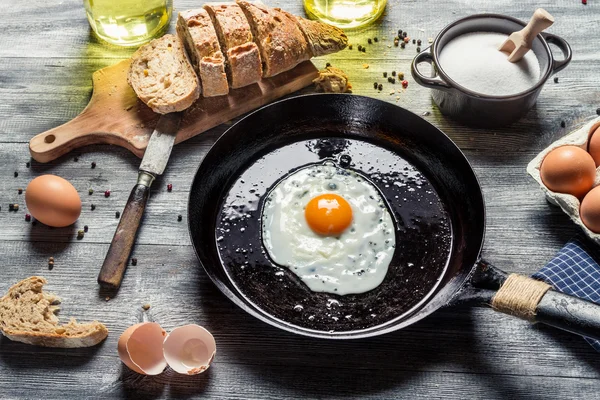 Fried egg on a pan served with homemade bread — Stock Photo, Image