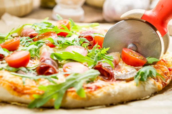 Cutting baked pizza with tomatoes and ham — Stock Photo, Image