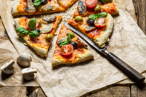 Frisch gebackene Pizza geteilt und auf Backpapier gegeben — Stockfoto