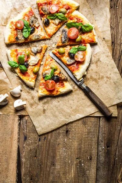 Frisch gebackene Pizza auf altem Holztisch serviert — Stockfoto