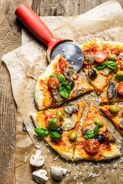 Styckning hemmagjord pizza på gamla tabellen — Stockfoto