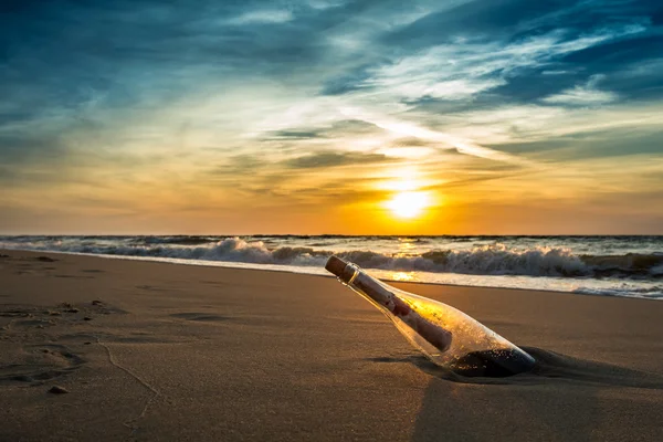 Flaschenpost am Strand gegen die untergehende Sonne — Stockfoto