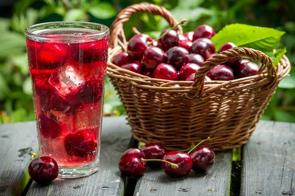 Свежесобранные сладкие вишни и сок из них со льдом — стоковое фото
