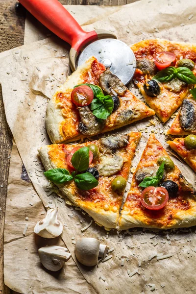 Hausgemachte Pizza auf altem Tisch schneiden — Stockfoto