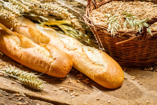 Two baguettes and a basket of grain — Stock Photo, Image