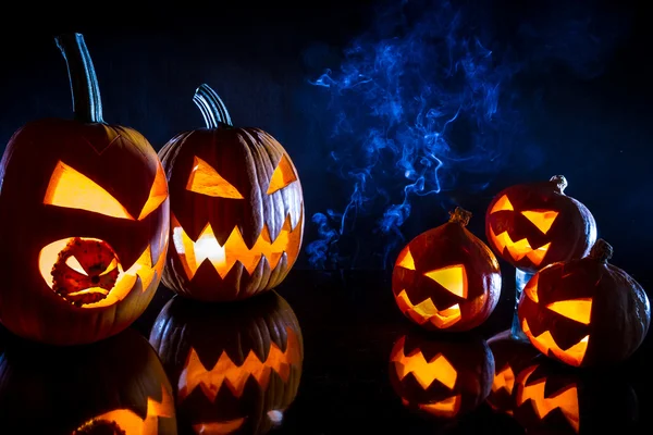 Calabazas pequeñas y grandes para Halloween con velas en un b negro — Foto de Stock