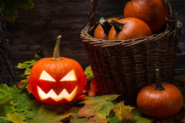 Pumpkins in wicker basket with leaves — Stock Photo, Image