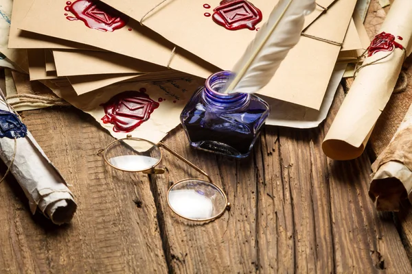 Närbild av blå bläckhorn och glasögon på bord fyllda med gamla mes — Stockfoto