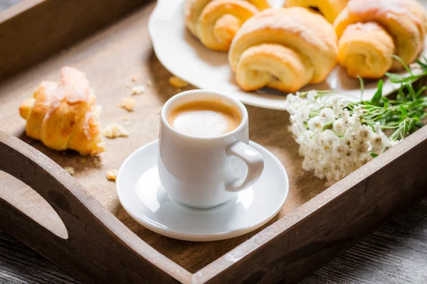 Frukost på sängen med espresso, blomma och croissant — Stockfoto