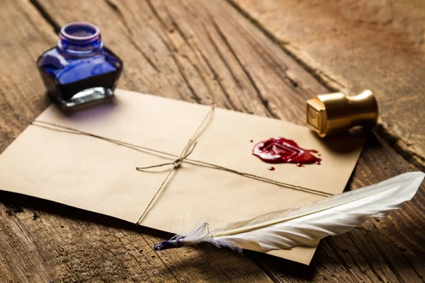 Closeup of feather on envelope with red sealant and inkwell — Stock Photo, Image