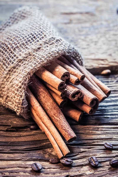 Cinnamon sticks in a burlap sack on the wooden table — Stock Photo, Image