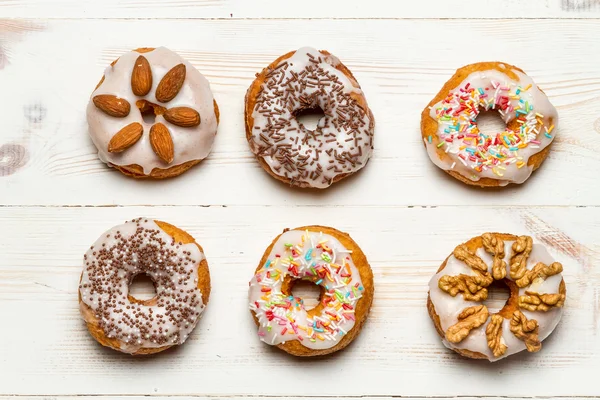 Six colorful donuts on old wooden table — Stock Photo, Image