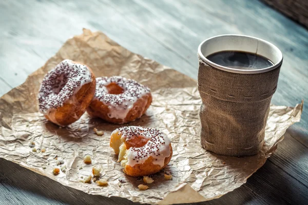 Nahaufnahme von heißem Kaffee und Donuts auf Papier — Stockfoto