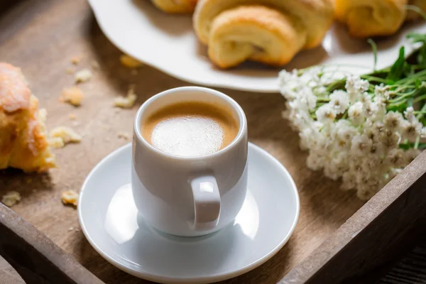 Frukost på sängen med espresso, blomma och croissant — Stockfoto