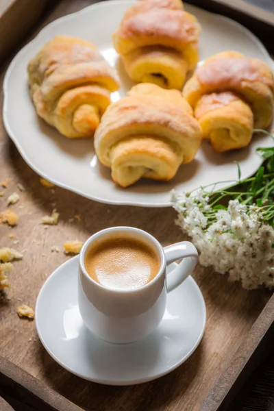 Frukost på sängen med espresso, blomma och croissant — Stockfoto
