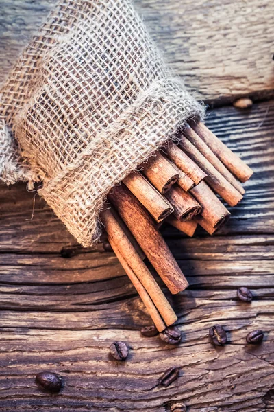 Cinnamon sticks in a burlap sack on the wooden table — Stock Photo, Image